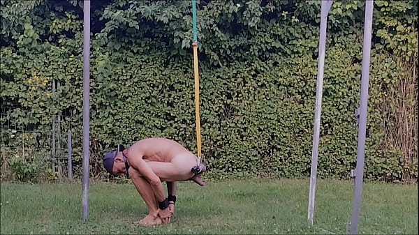 naked pathetic slave during outdoor party, handcuffed, testicles stretched in humbler, BDSM CBT